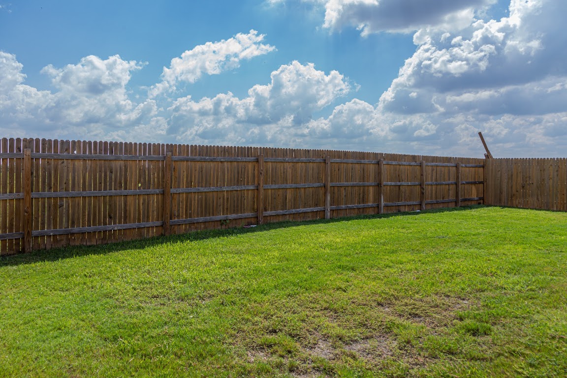 15225 Harkness Pass Austin, TX 78725 - Photo 22 of 23 a view of a backyard with grass and wooden fence