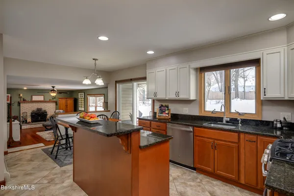 a kitchen with kitchen island granite countertop a sink stove and cabinets