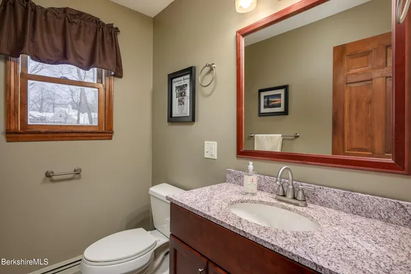 a bathroom with a granite countertop toilet sink and mirror