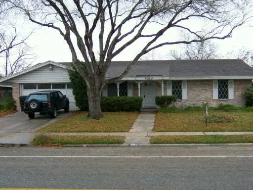 a view of a white house next to a yard with a large tree