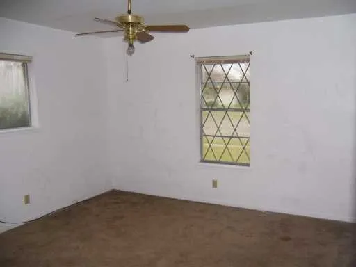 an empty room with windows and fan