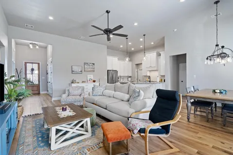 a living room with furniture kitchen view and a chandelier
