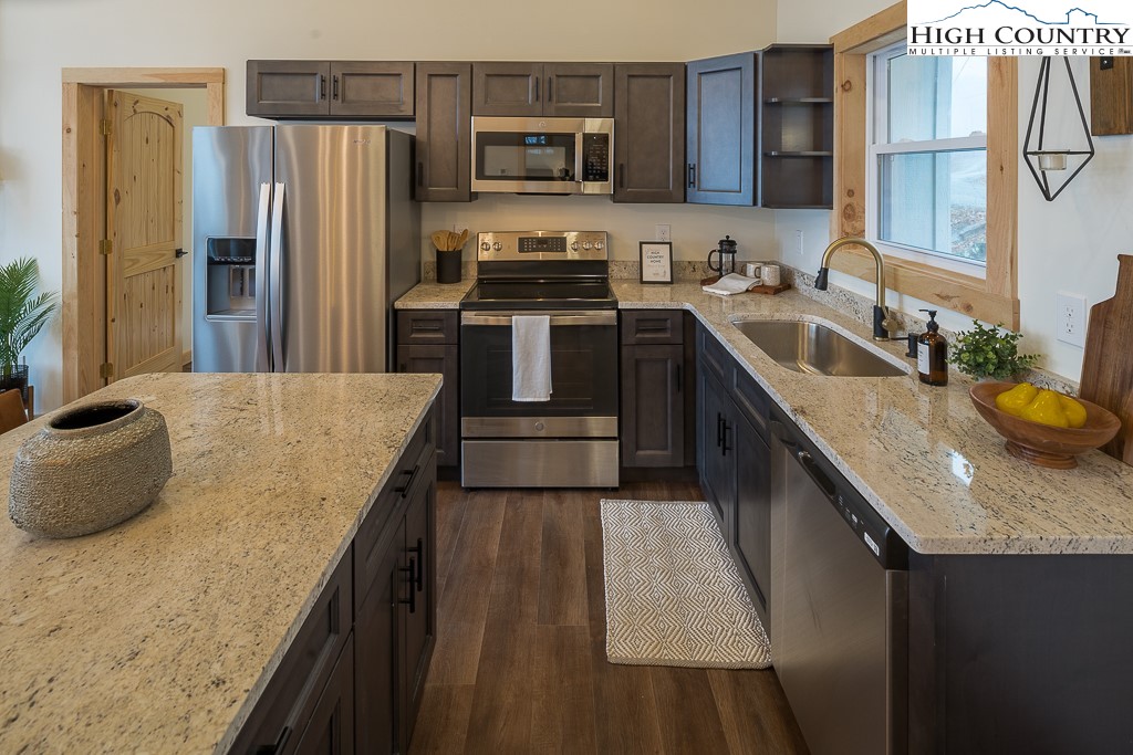 232 Wild Daisy Lane Beech Mountain, NC 28604 - Photo 16 of 49 a kitchen with stainless steel appliances granite countertop a sink a stove and a refrigerator