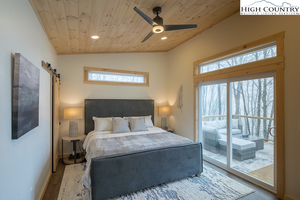 232 Wild Daisy Lane Beech Mountain, NC 28604 - Photo 25 of 49 a bedroom with a large bed and a chandelier