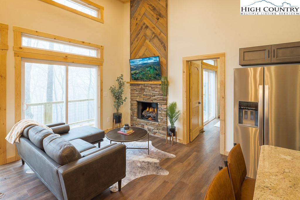 232 Wild Daisy Lane Beech Mountain, NC 28604 - Photo 4 of 49 a living room with furniture a fireplace and a floor to ceiling window