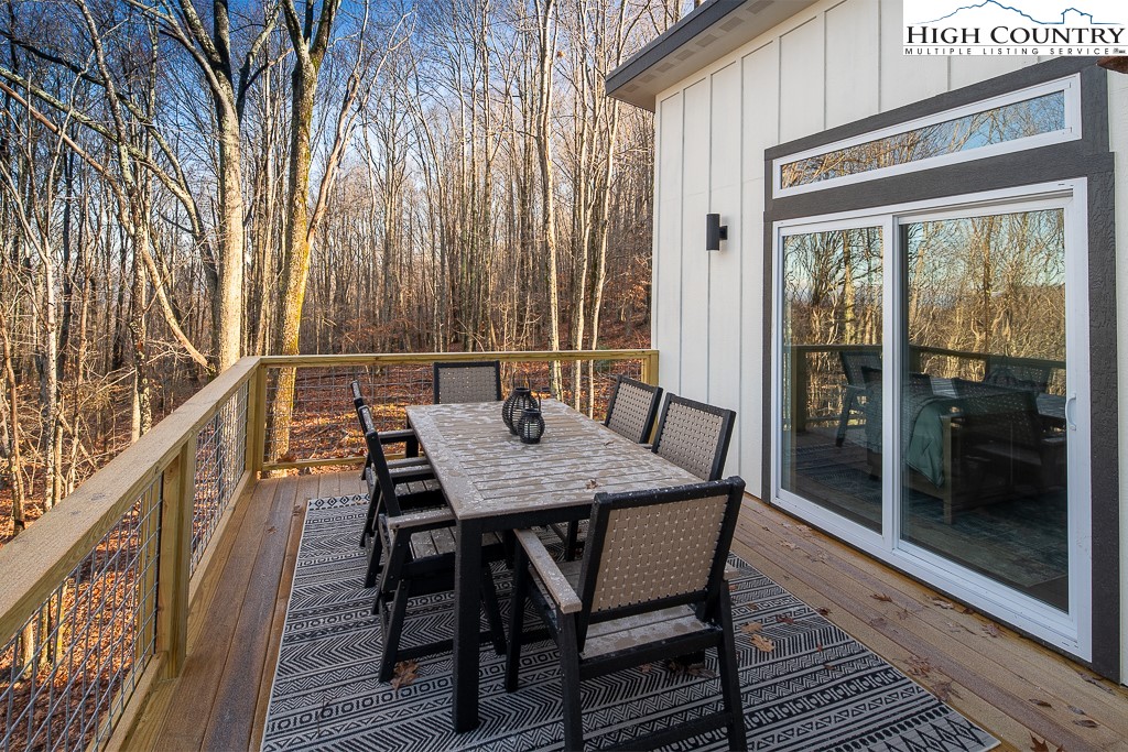 232 Wild Daisy Lane Beech Mountain, NC 28604 - Photo 45 of 49 a view of a patio with table and chairs with wooden floor and floor to ceiling window