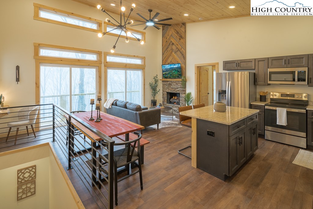 232 Wild Daisy Lane Beech Mountain, NC 28604 - Photo 8 of 49 a kitchen with stainless steel appliances granite countertop a stove top oven a sink dishwasher a dining table and chairs with wooden floor