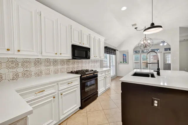a kitchen with stainless steel appliances a sink dishwasher stove refrigerator and white cabinets with wooden floor