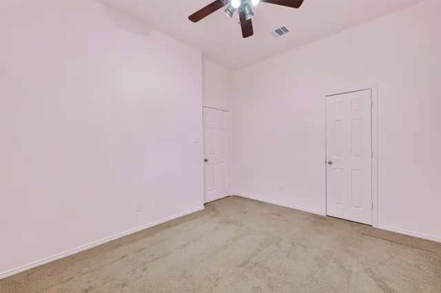 an empty room with a fan & a window