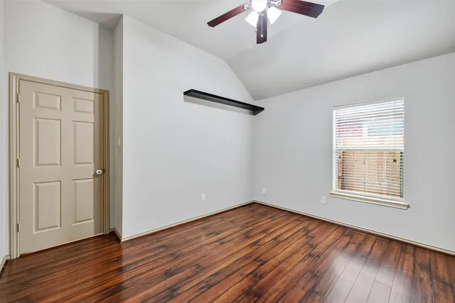 an empty room with wooden floor chandelier fan and windows