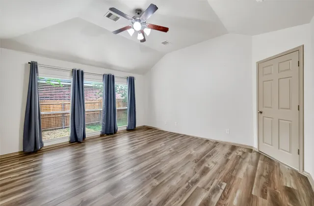 an empty room with wooden floor and windows
