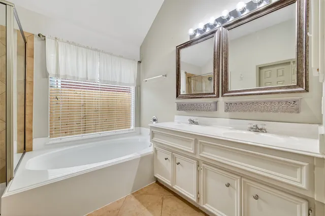 a bathroom with a tub a sink and mirror