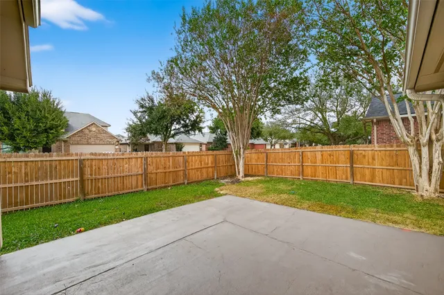 a view of a backyard with fence and trees