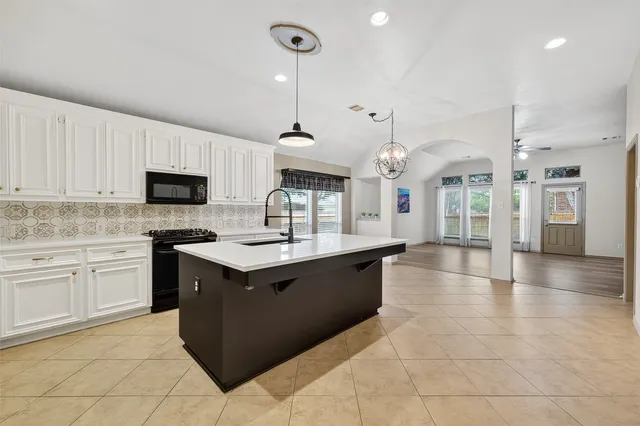 a large kitchen with stainless steel appliances kitchen island granite countertop a sink and a stove