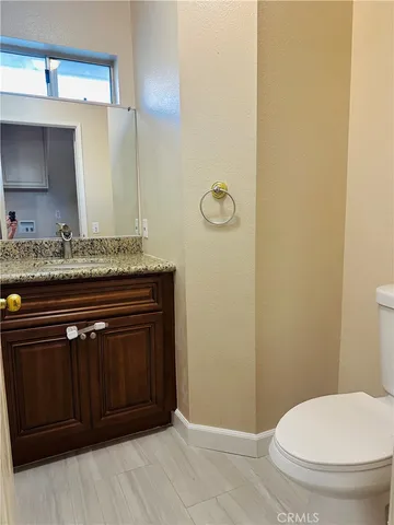 a bathroom with a granite countertop sink and a toilet