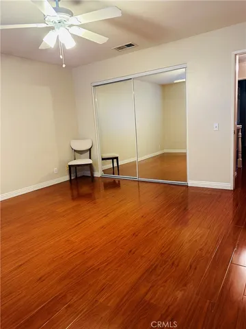 an empty room with wooden floor fan and windows