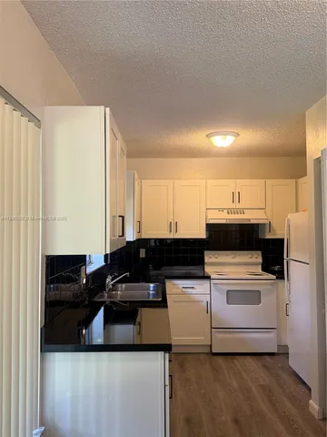 a kitchen with kitchen island a sink a stove and white cabinets