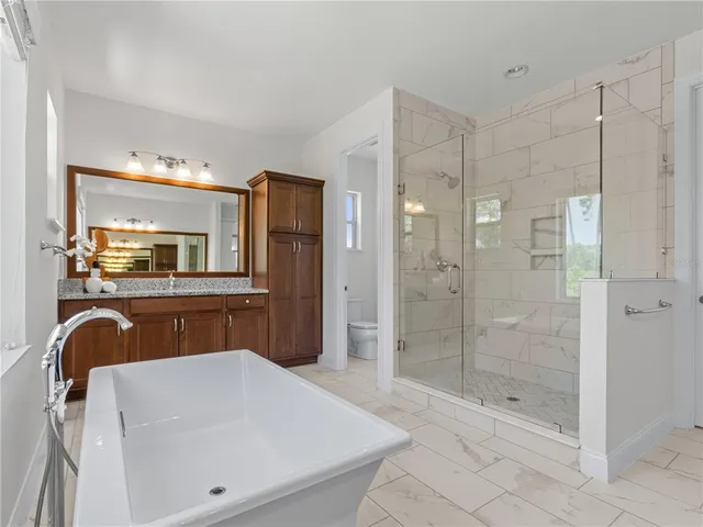 a bathroom with a bathtub shower sink mirror and toilet