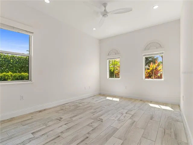 an empty room with wooden floor ceiling fan and windows