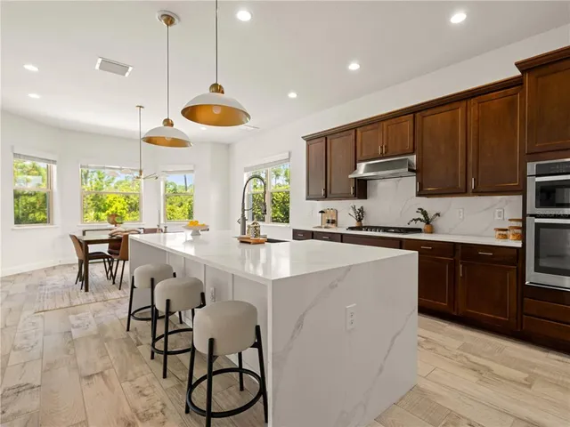 a kitchen with stainless steel appliances granite countertop a stove a sink a center island and cabinets
