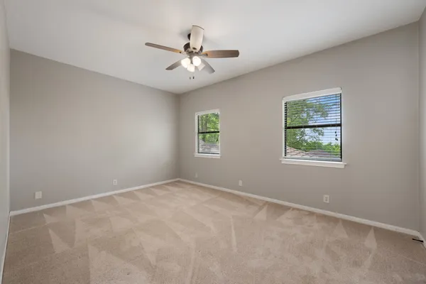 an empty room with windows and ceiling fan