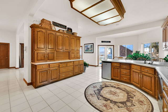 1085 Windsor Drive Provo, UT 84604 - Photo 20 of 83 Kitchen featuring brown cabinets, light countertops, a peninsula, stainless steel dishwasher, and light tile patterned floors