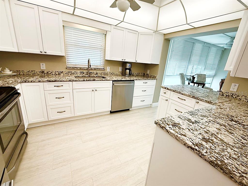 4455 Duhme Road, Unit 103 St. Petersburg, FL 33708 - Photo 10 of 37 a kitchen with granite countertop a sink stove and cabinets