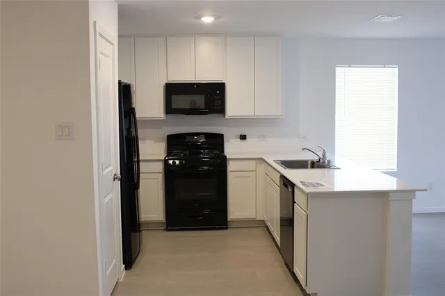 a kitchen with white cabinets and black appliances