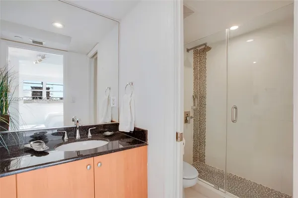 a bathroom with a granite countertop sink toilet and shower