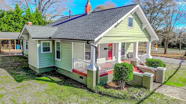 a view of small white house with a small yard and potted plants