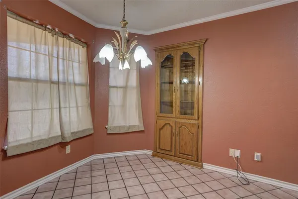 a view of an empty room with window and chandelier fan