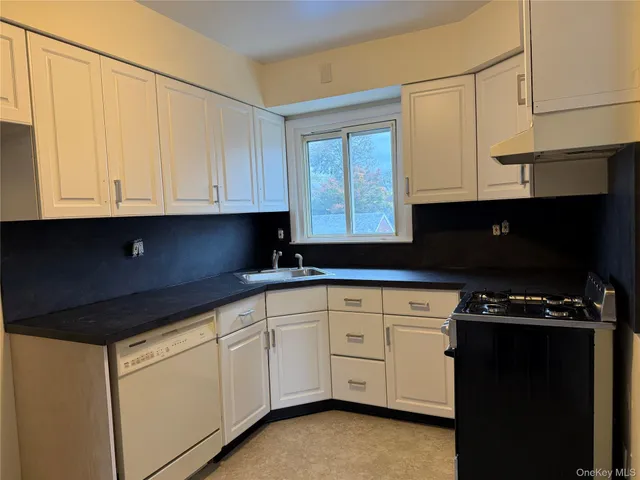 a kitchen with white cabinets and black appliances