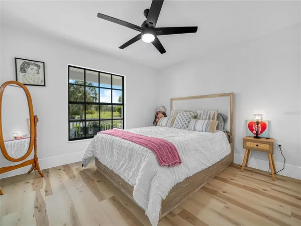 a bedroom with a bed a dresser next to a window with a chandelier