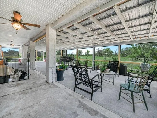 a view of a patio with table and chairs potted plants with floor to ceiling window