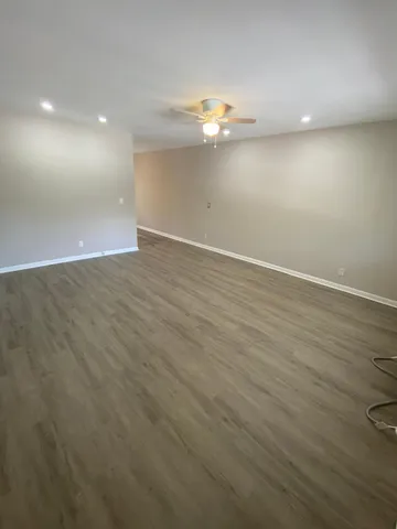 an empty room with wooden floor and chandelier fan