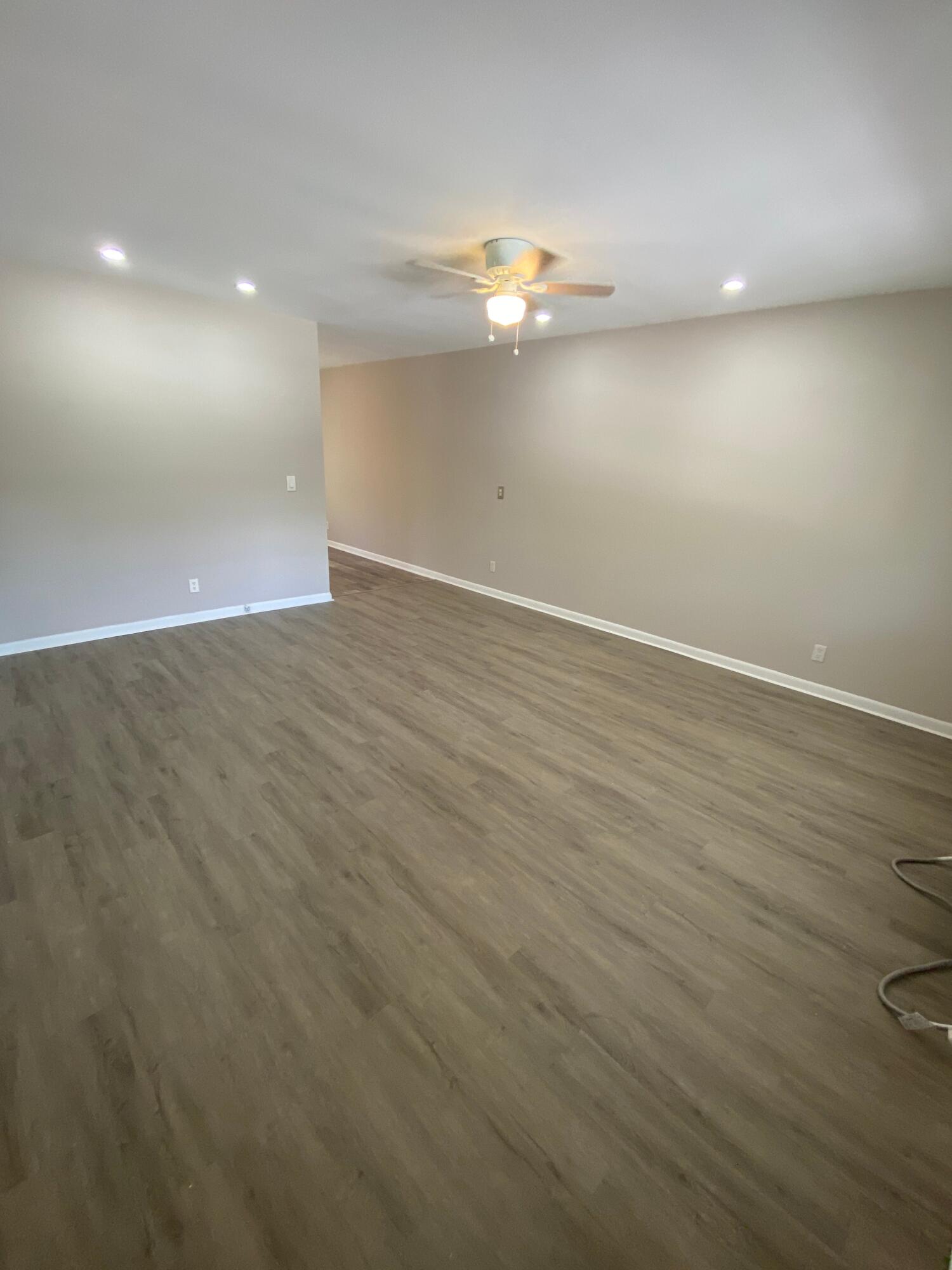 612 Prosperity Farms Road, Unit 2 North Palm Beach, FL 33408 - Photo 2 of 14 an empty room with wooden floor and chandelier fan