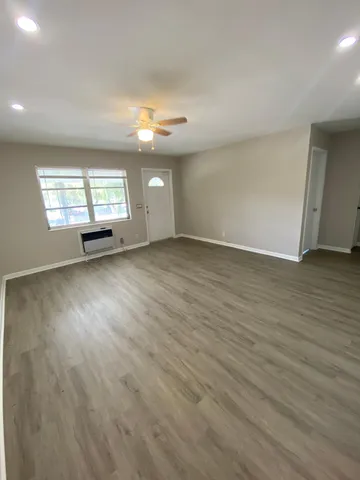an empty room with wooden floor and windows