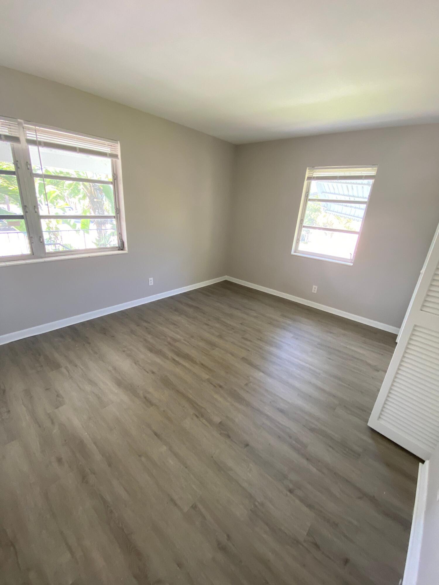 612 Prosperity Farms Road, Unit 2 North Palm Beach, FL 33408 - Photo 8 of 14 an empty room with wooden floor and windows