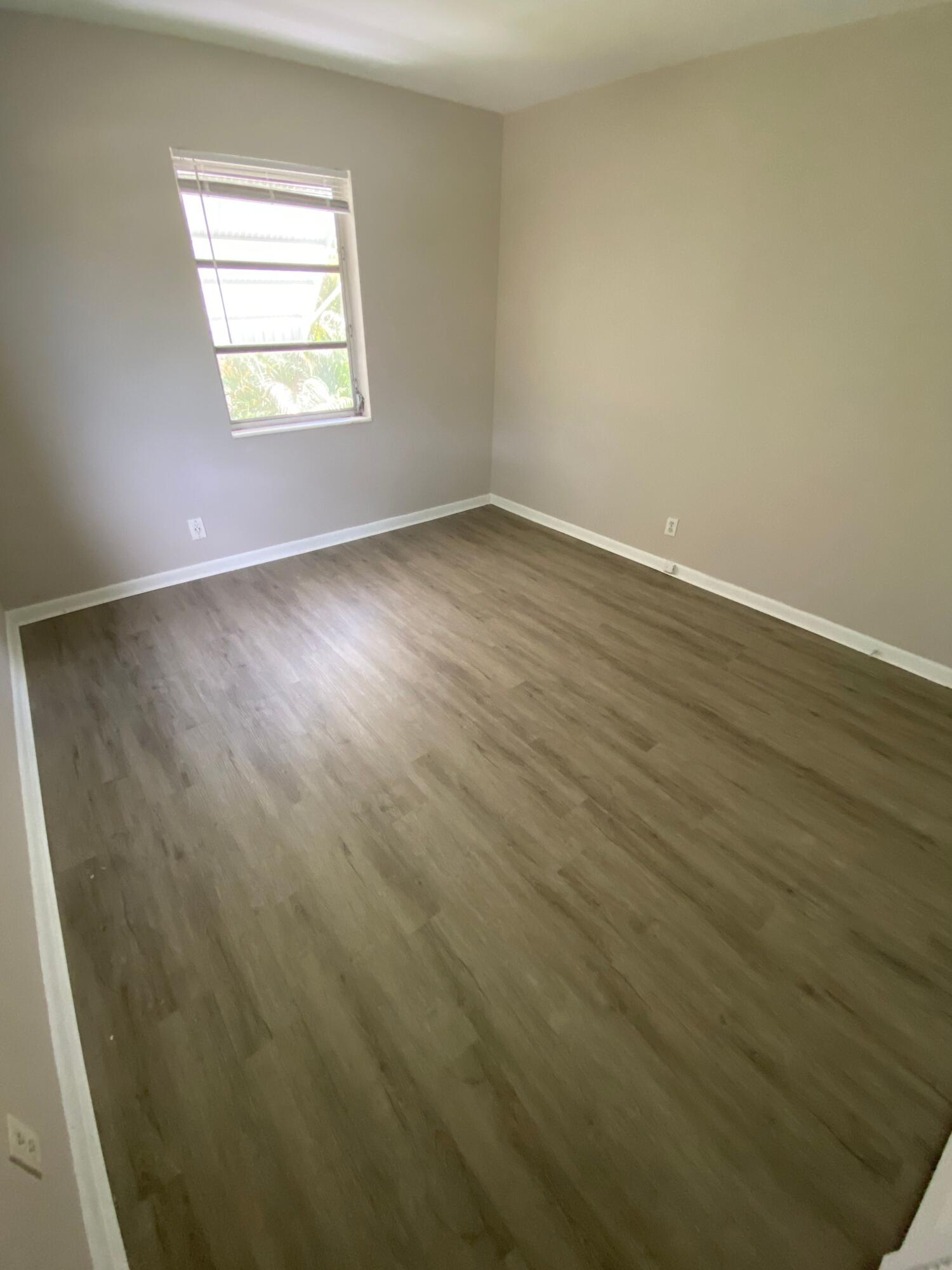 612 Prosperity Farms Road, Unit 2 North Palm Beach, FL 33408 - Photo 10 of 14 an empty room with wooden floor and windows