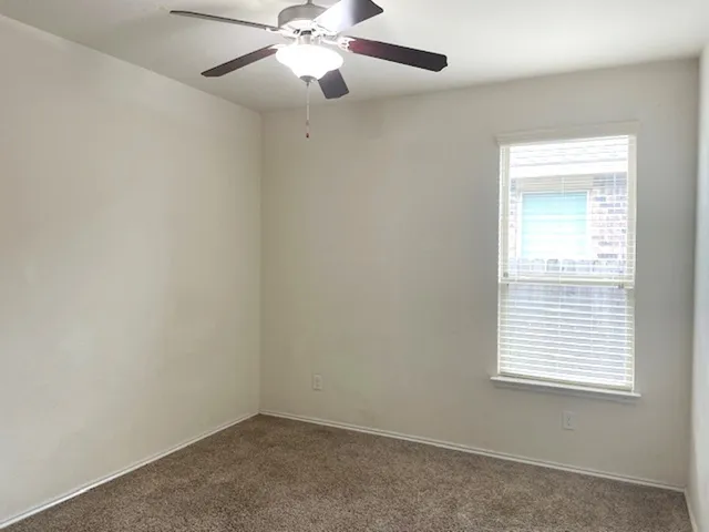 an empty room with a chandelier fan and windows