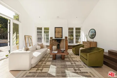 a living room with furniture a fireplace and a floor to ceiling window