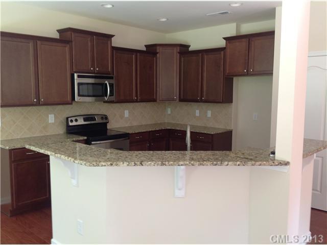 78102 Rillstone Drive, Unit 203 Lancaster, SC 29720 - Photo 6 of 9 a kitchen with stainless steel appliances granite countertop a refrigerator a sink a stove a microwave and wooden cabinets