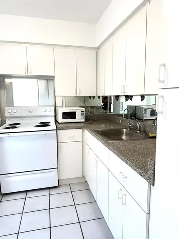 a kitchen with a sink a stove and white cabinets