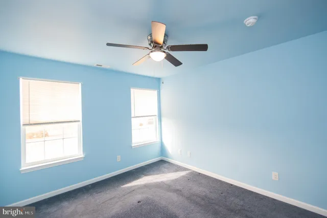 an empty room with closet and a ceiling fan