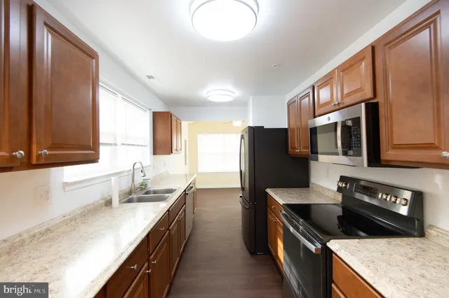 a large kitchen with stainless steel appliances granite countertop a sink stove and refrigerator