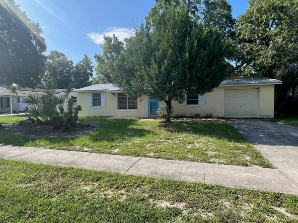a view of a yard in front of a house with large tree