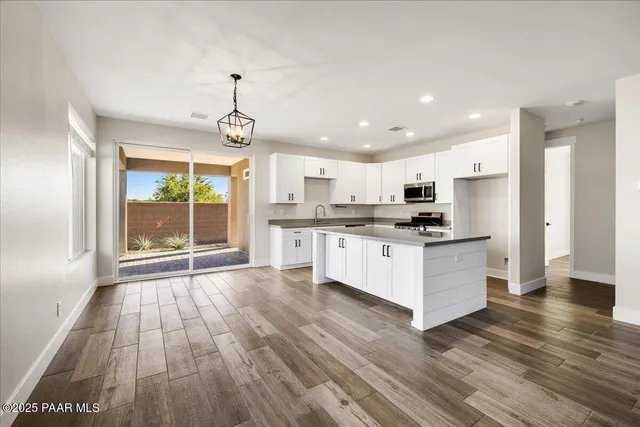 a large white kitchen with stainless steel appliances granite countertop a stove and a window