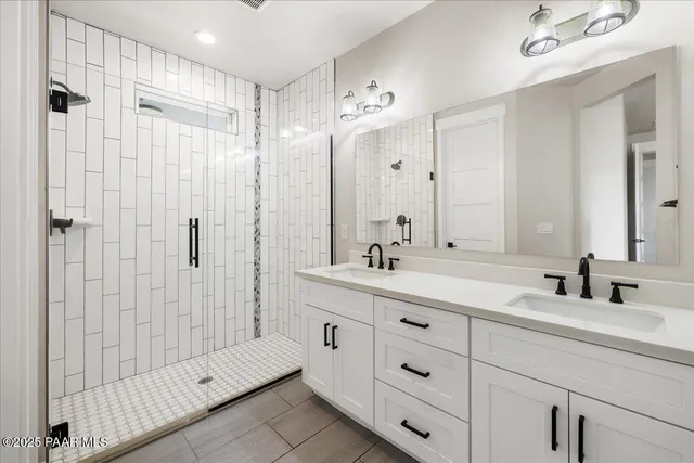 a bathroom with a double vanity sink mirror and shower