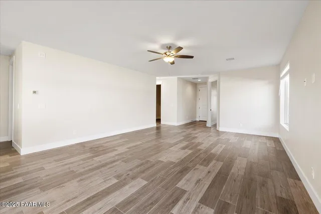 a view of empty room with wooden floor and fan