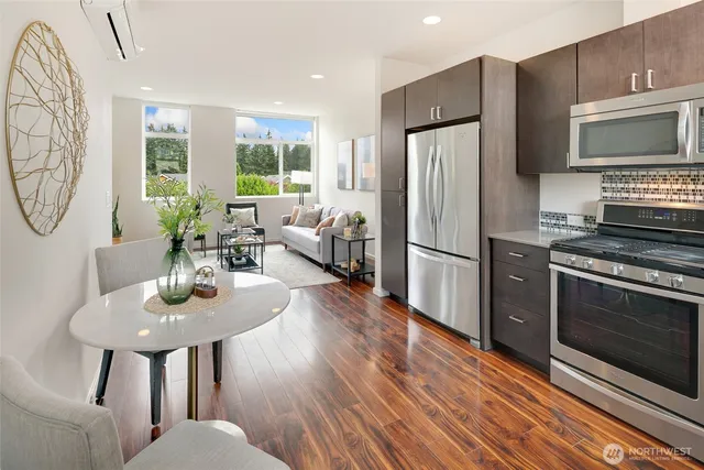 a kitchen with stainless steel appliances granite countertop a refrigerator a stove a sink dishwasher a dining table and chairs with wooden floor